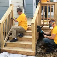 deck medic yellow shirt workers sanding wood deck